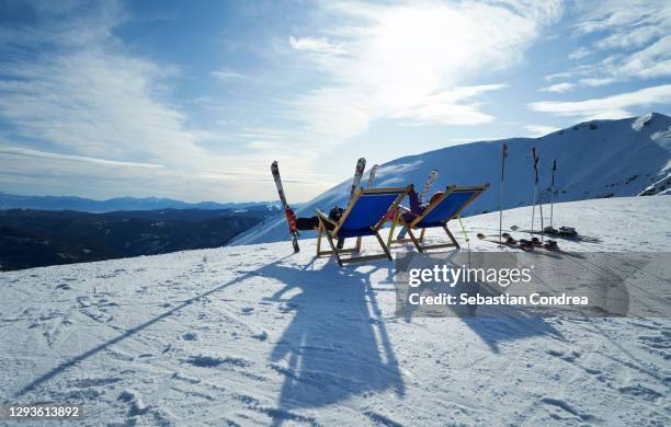 lounge chairs, mountain skis with climbing skins, ski resort. - apres ski stock pictures, royalty-free photos & images