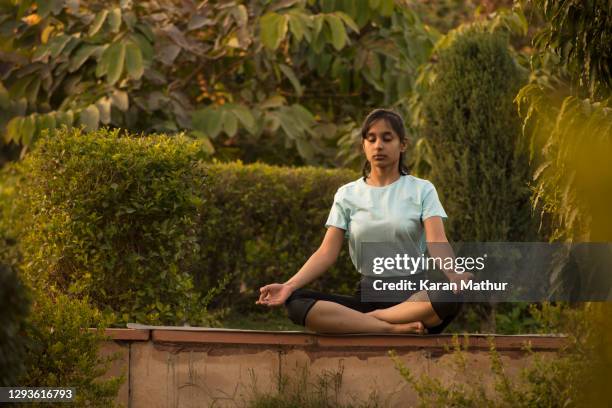 indian teenager girl doing yoga & meditation in park stock photo - buddhism india stock pictures, royalty-free photos & images