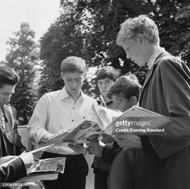 English footballer Alan Ball Jr of Blackpool FC and the England team signs autographs for fans during the World Cup Final, London, UK, 30th July 1966.