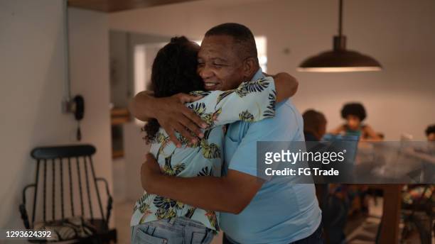 father embracing daughter at home - black family reunion stock pictures, royalty-free photos & images