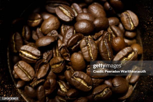 moody tone, close-up view of roasted coffee bean inside grinder machine. - arabica kaffee getränk stock-fotos und bilder