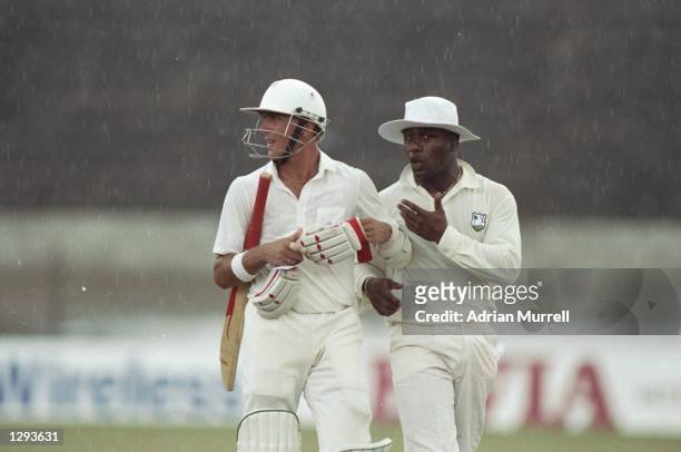Alec Stewart of England ignores West Indies Captain Desmond Haynes after rain stops play during the Third Test match at Queen's Park Oval in...