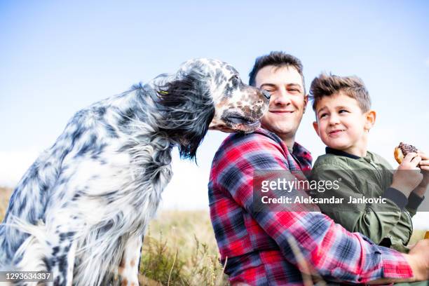 ein schöner hund schnüffelt einen niedlichen jungensnack auf einer bergwanderung - father son outdoor celebration stock-fotos und bilder