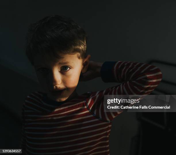 little boy peers out of shadows - boy looking up stock pictures, royalty-free photos & images