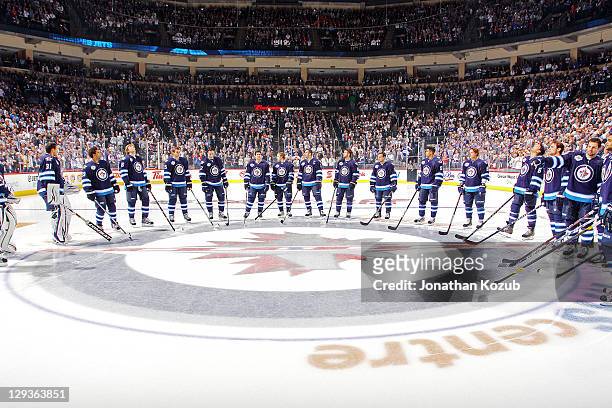 Members of the Winnipeg Jets gather around the Centre Ice logo during pre-game introductions prior to the Winnipeg Jets taking on the Montreal...