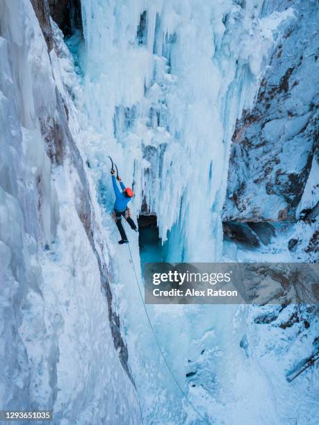 overhead shot of a male ice climber climbs a tall, vertical frozen water fall in british columbias interior - frozen waterfall stockfoto's en -beelden