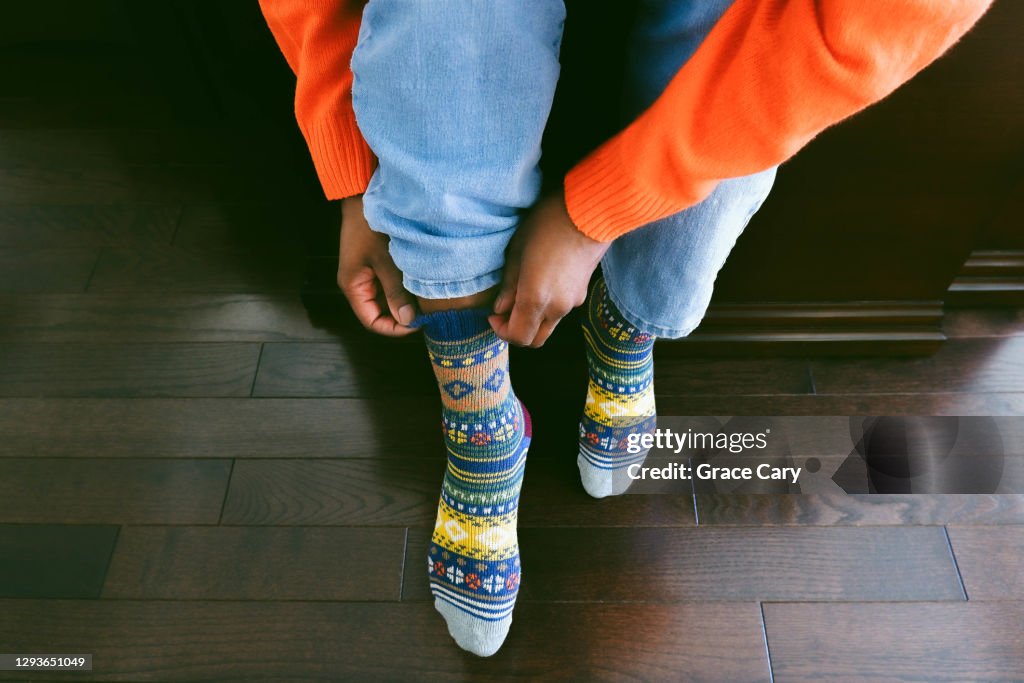 Woman Puts on Colorful Wool Socks With Light Blue Jeans