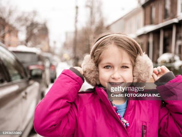 ragazza su una strada della città con la neve - earmuffs foto e immagini stock
