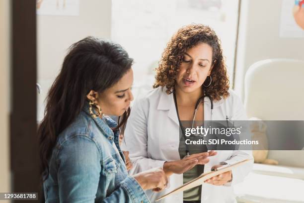 pediatrician talks with patient's mother - doctor talking imagens e fotografias de stock