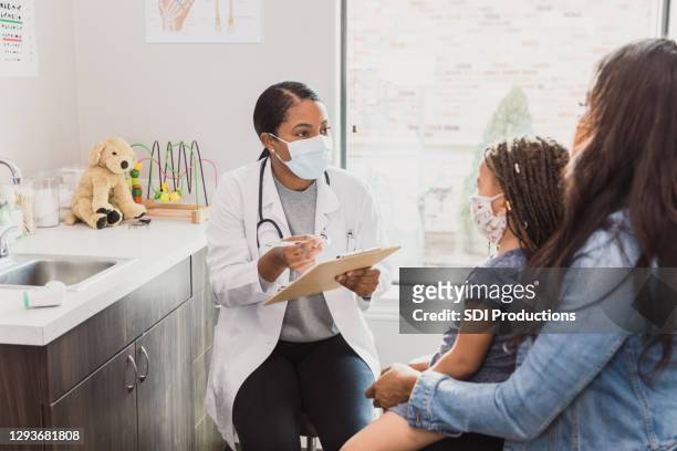 female pediatrician talks with patient's mother - pediatrician covid stock pictures, royalty-free photos & images