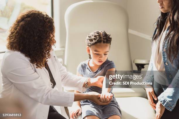 pediatrician examine young girl's injured arm - orthopedist stock pictures, royalty-free photos & images