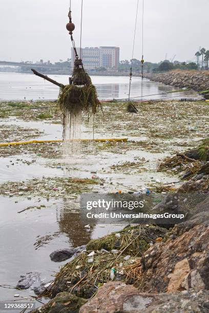 Cranes picking up garbage debris after first rain of the season. The Garbage boom on the Los Angeles River in Long Beach was built in 2001. Urban...