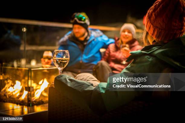 friends sitting by fire at ski apres at night. - apres ski stock pictures, royalty-free photos & images