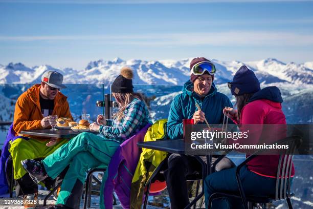 group of friends enjoying apres-ski at top of whistler mountain. - apres ski stock pictures, royalty-free photos & images