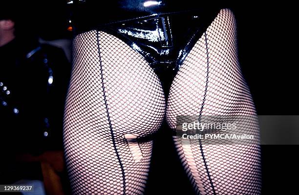 Woman wearing a leather thong and laddered fish net tights, UK, 1980's