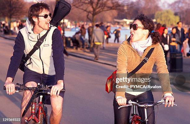 Man and woman, on bicycles, riding through a park, London, UK 2004