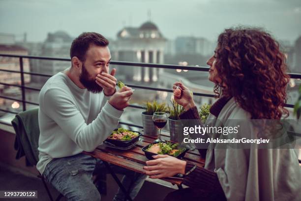 couple smiling and enjoying date with lunch on building rooftop - dating stock pictures, royalty-free photos & images