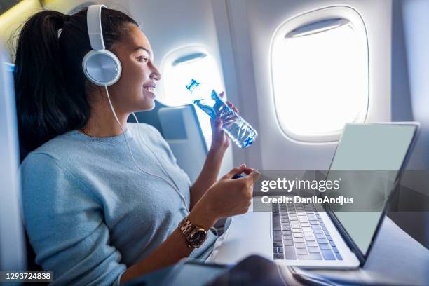 de jonge vrouwelijke freelancer geniet van haar vlucht - first class plane stockfoto's en -beelden