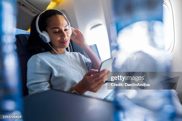 frau mit kopfhörern im flugzeug hört musik - first class plane stock-fotos und bilder