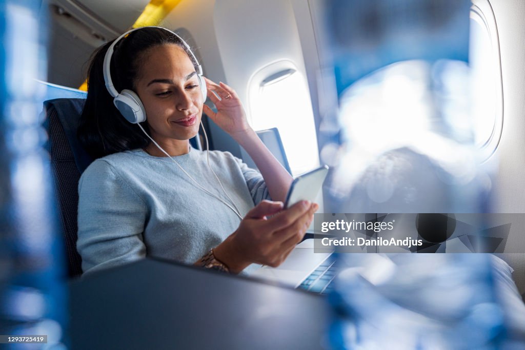 Woman with headphones on a plane listening music