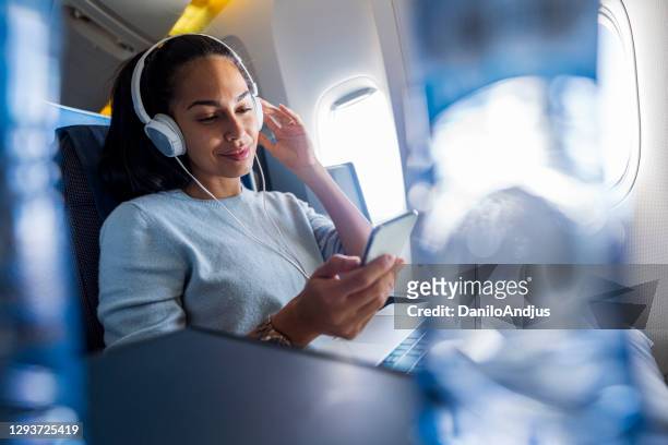 woman with headphones on a plane listening music - comfortable flight stock pictures, royalty-free photos & images