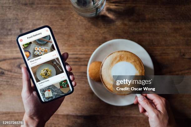 high angle view of woman ordering food delivery on smartphone while enjoying coffee - phone on table stock pictures, royalty-free photos & images