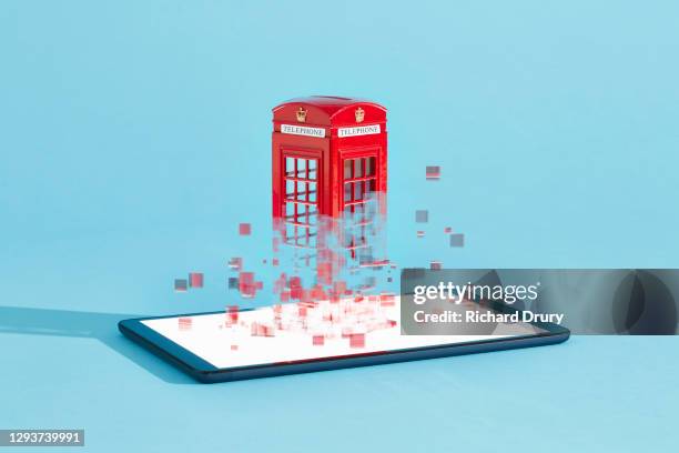 a british telephone box emerging from a digital tablet - break through concept stockfoto's en -beelden