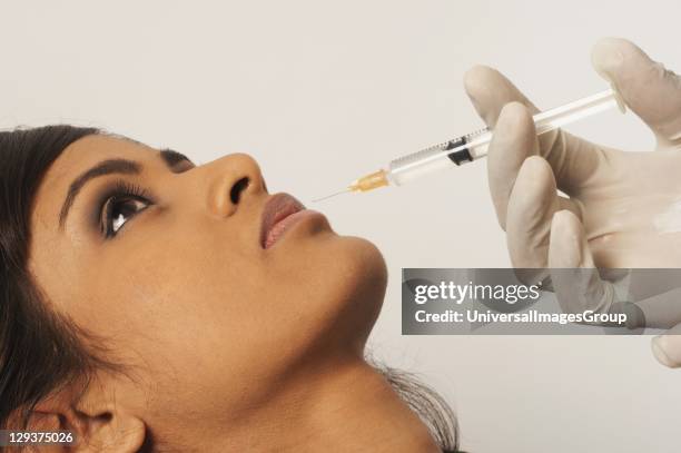 Doctor injecting collagen into young womans lip