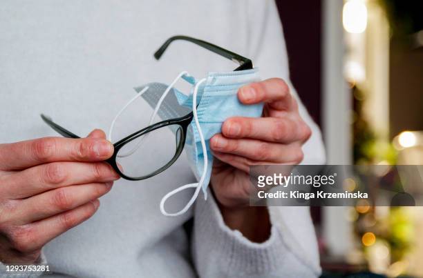 cleaning glasses with face covering - misinformation stock-fotos und bilder