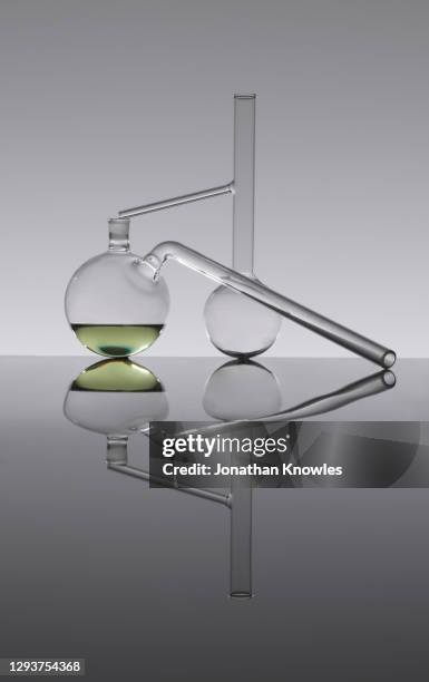 green liquid in abstract science retort flask - destillation stock-fotos und bilder