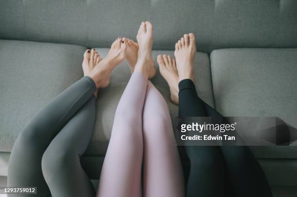 asian chinese legs with yoga pants resting on sofa legs crossed - skinny trousers stock pictures, royalty-free photos & images