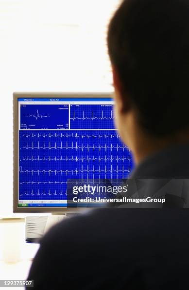Doctor looking at computer screen reading out Exercise Stress Test ...