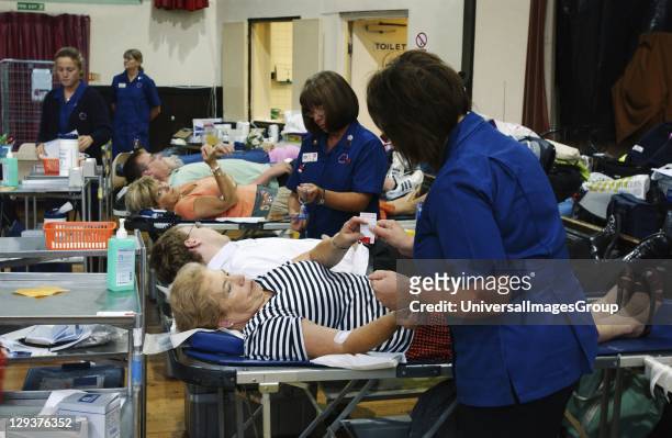 Nurses attend blood donors on beds during session at NHS National Blood Service collection centre