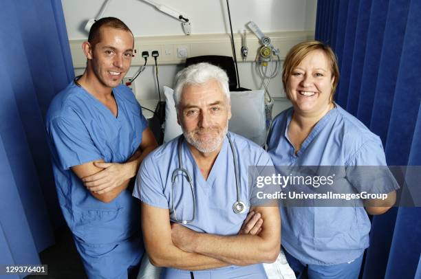 Bearded surgeon and two members of surgical team in hospital ward