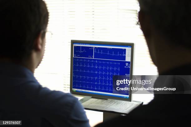 Doctors looking at screen, Doctors reviewing on a computer monitor an electrocardiogram recording of a patients cardiac cycle produced by an...