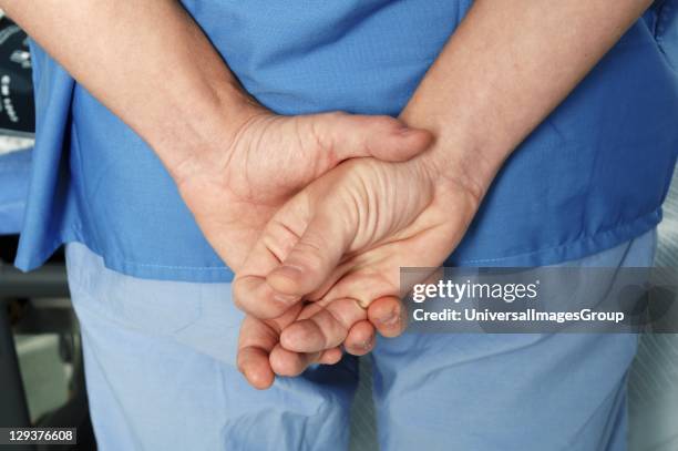 Surgeons hands held together behind back, midsection