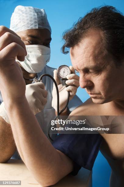 Middle-aged man has his blood pressure measured by doctor using sphygmomanometer