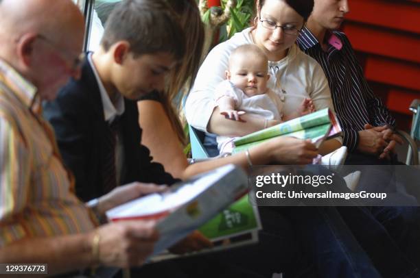 Group of patients including baby, sitting in waiting room of surgery