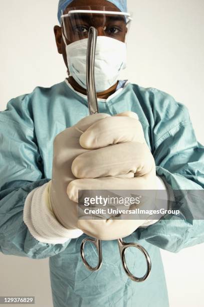 Portrait of surgeon holding pair of forceps in his clasped hands