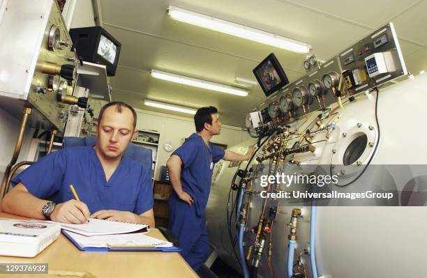 Hyperbaric technologist speaking to patient in chamber through radio human handset, The technologist is able to see the patient through a monitor as...