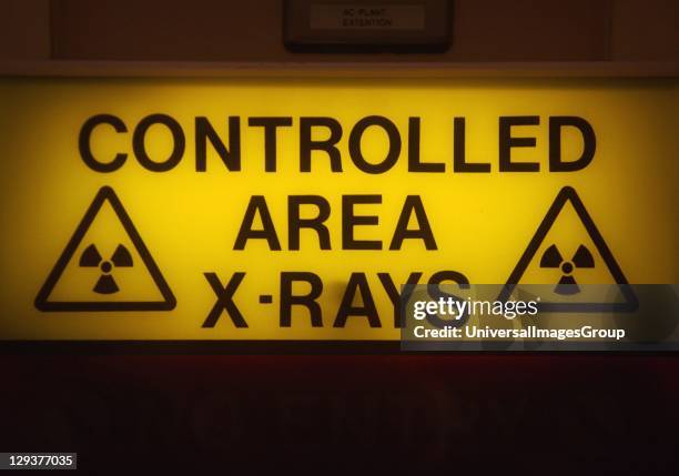 Illuminated x-ray signs in hospital, The phrase Controlled area. X-rays is bordered by radiation hazard signs. The light is switched on, indicating...