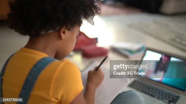 rear view of a elementary age girl studying watching online classes at home - afro back stock pictures, royalty-free photos & images