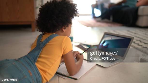 rear view of a elementary age girl studying watching online classes at home - virtual coach stock pictures, royalty-free photos & images