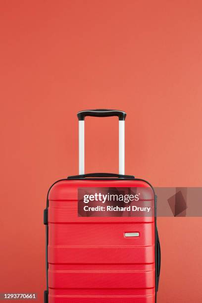 a red suitcase on a red background - koffer niemand stock-fotos und bilder