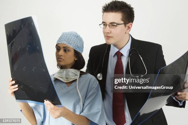 Studio shot of surgeon and doctor looking at patient x-rays