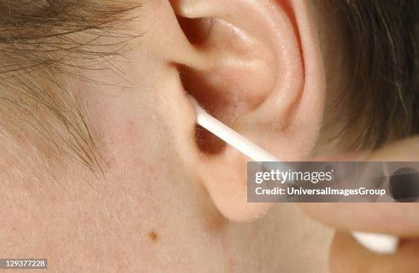 Man cleaning his ear canal with cotton bud, close-up