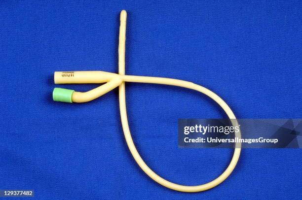 Paediatric foley catheter on blue table, This is often used to continually drain urine from the bladder following surgery when catheterization is...