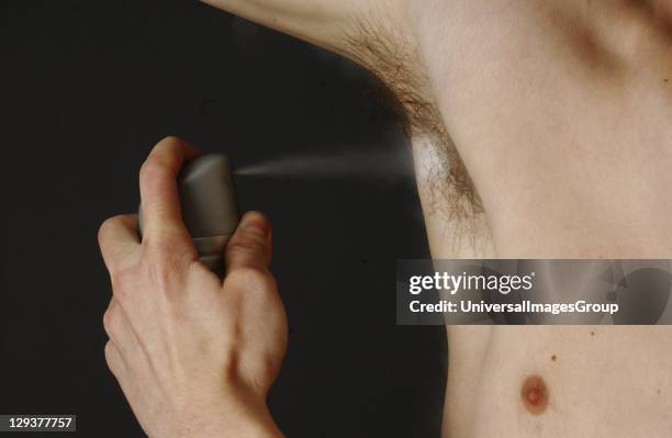 Man spraying an aerosol deodorant under his arm, close-up