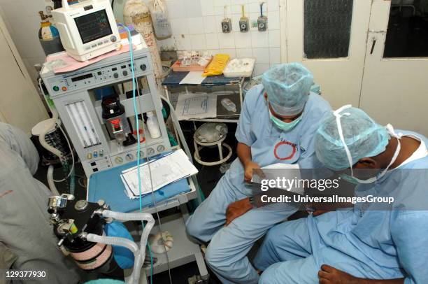 Anaesthetists check patients notes, while monitoring patients vital signs on anesthetic machine. Sudan, Africa.