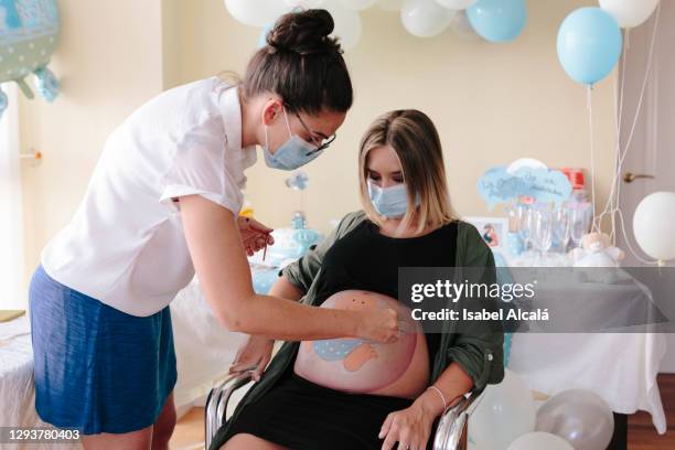 pregnant young woman being painted at her baby shower - baby shower - fotografias e filmes do acervo